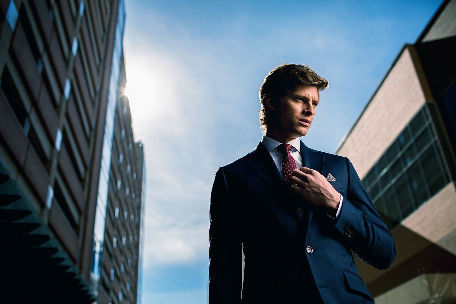 a man in a suit and tie is adjusting his tie in front of a building .