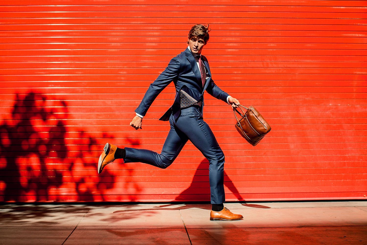 a man in a suit and tie is running with a briefcase in front of a red garage door .