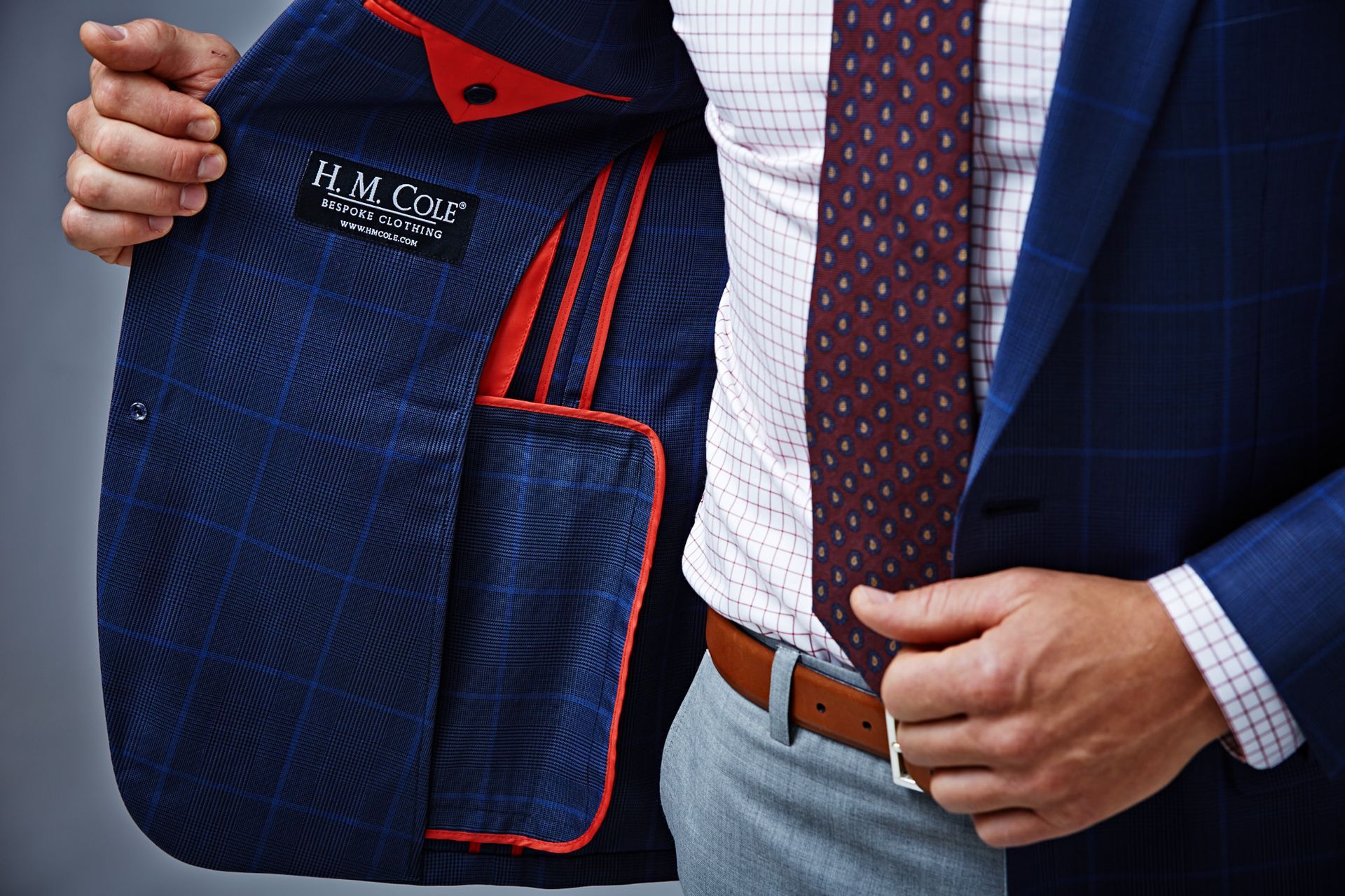 A man in a suit and tie is showing the inside of his jacket