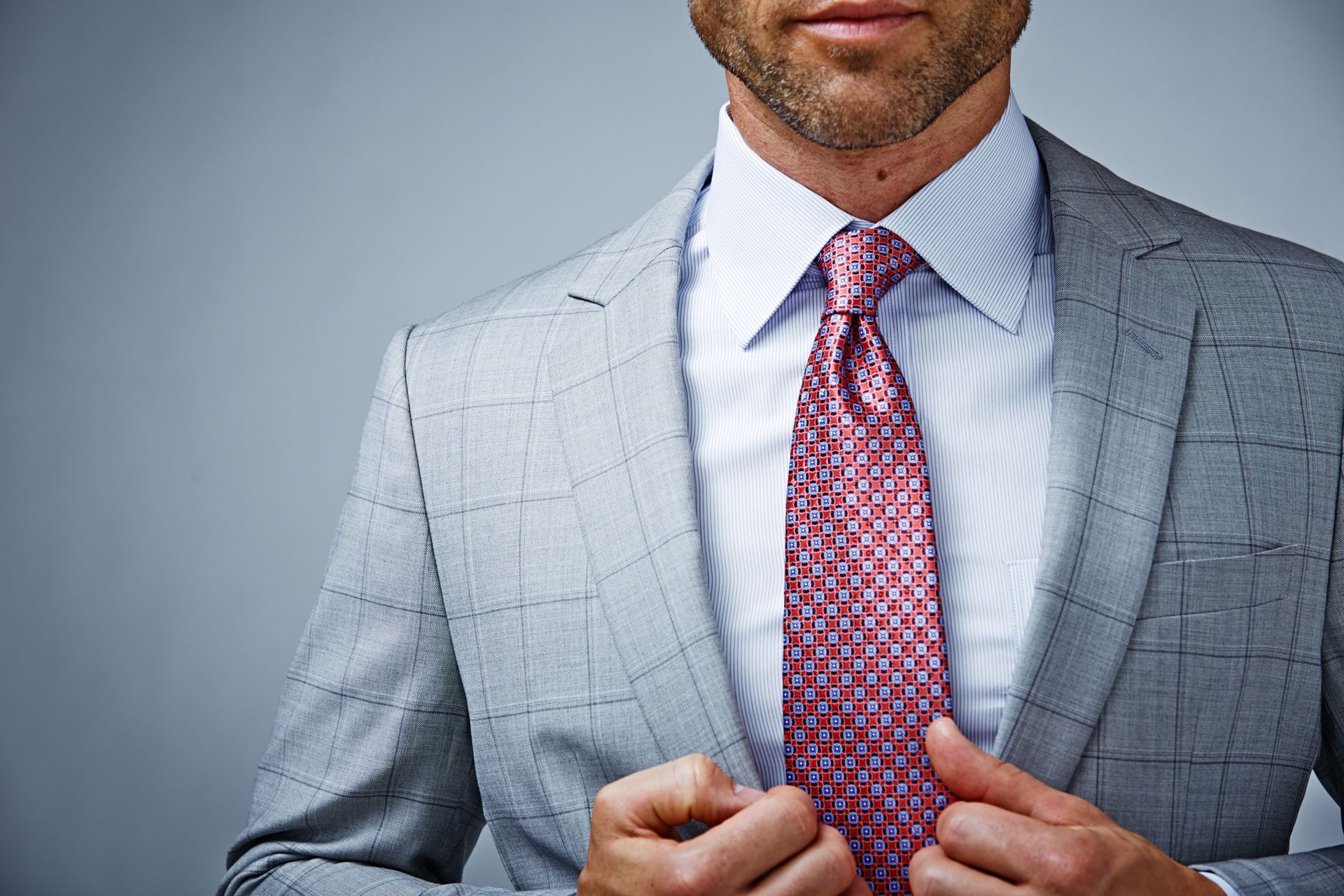 A man in a suit and tie is adjusting his tie.