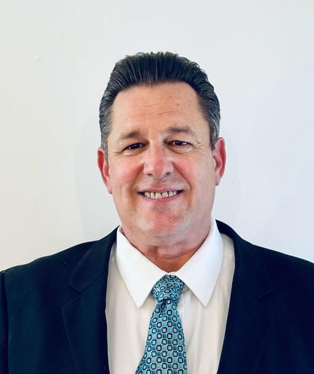 A man in a suit and tie is smiling for the camera.