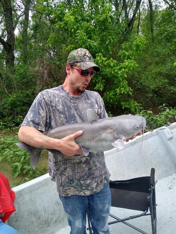 A man is holding a large fish in his hands while standing on a boat.