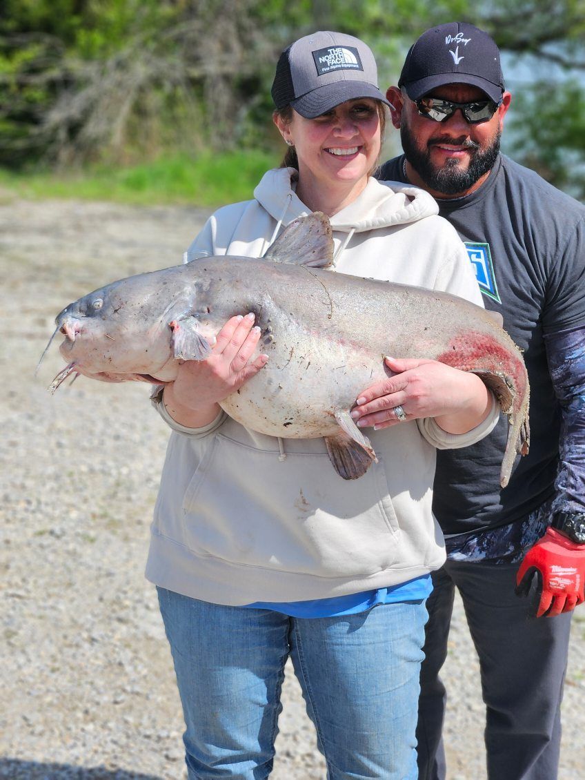 A man and a woman are holding a large fish.