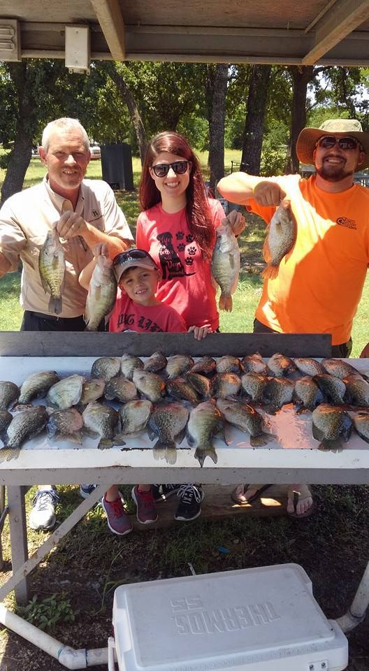 A group of people are standing around a table holding fish.