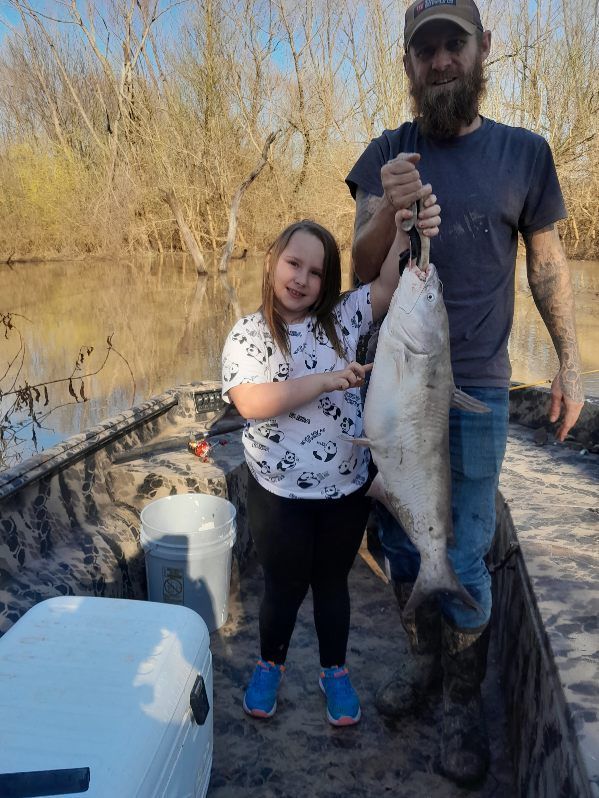 A man and a little girl are holding a large fish.