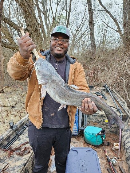 A man is holding a large catfish in his hands.