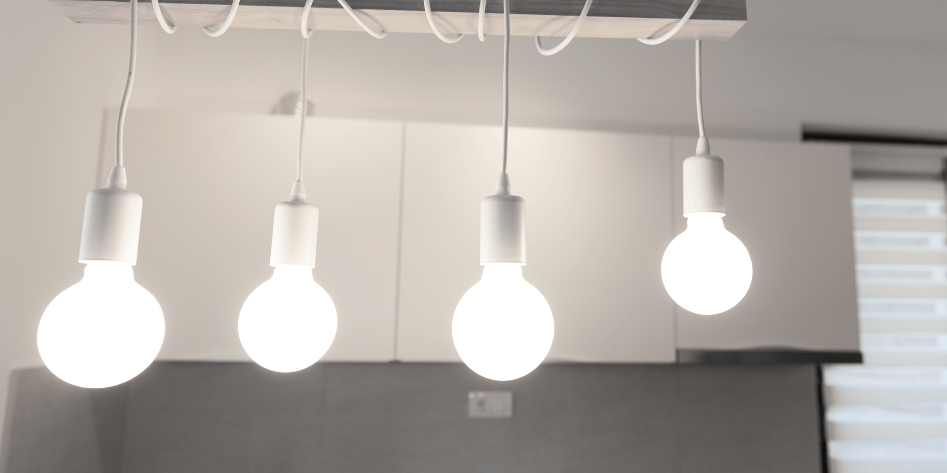 Four hanging light bulbs illuminate a kitchen.