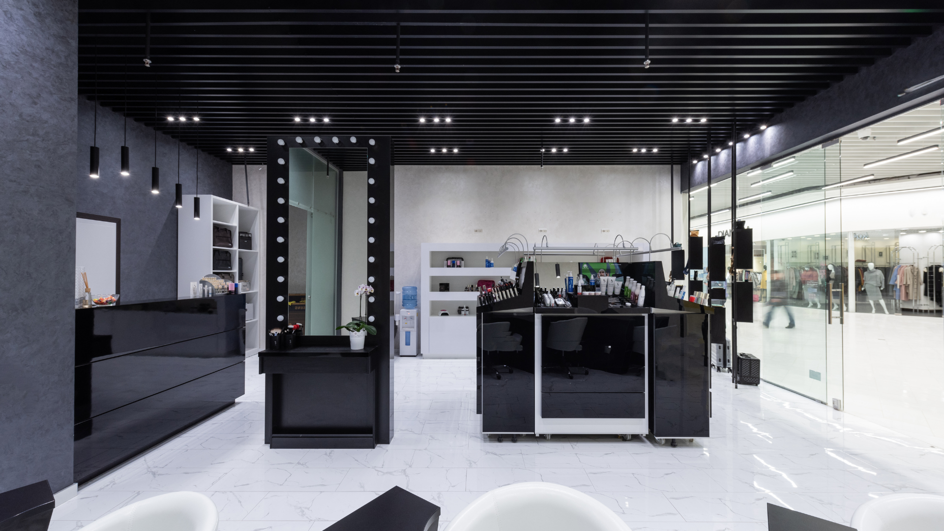Modern, black and white salon interior with makeup stations, mirrors, and retail displays.