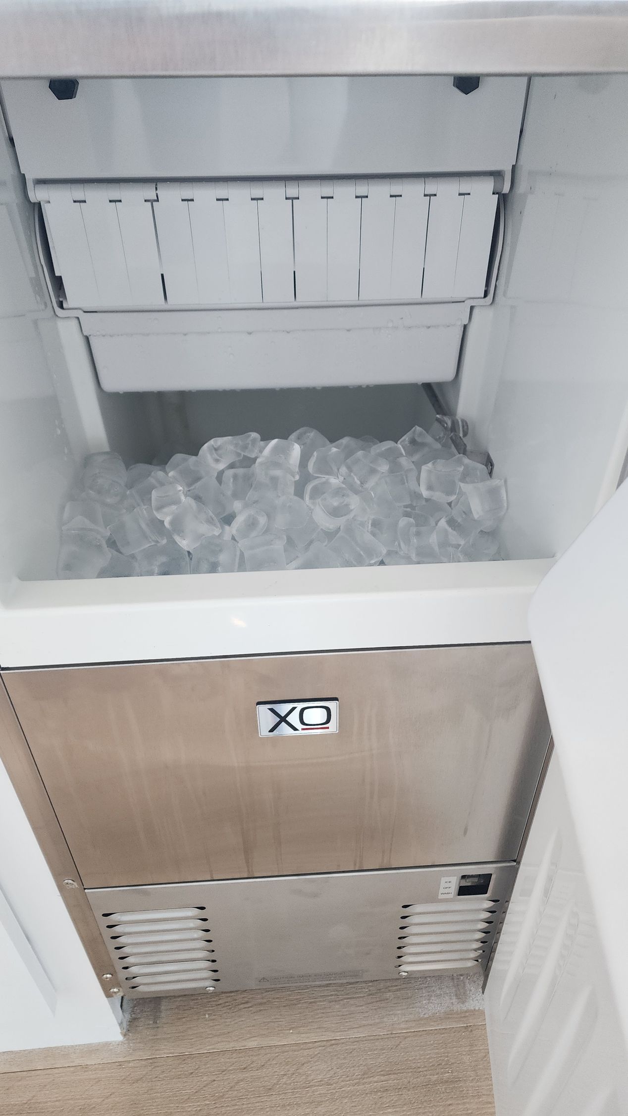 An interior view of a commercial ice machine with a bin full of clear, cube-shaped ice.