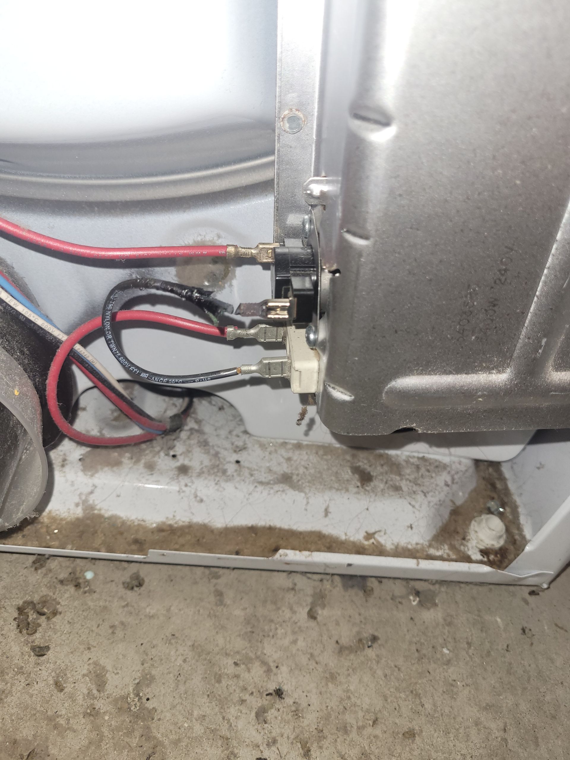 Close-up of refrigerator wiring and compressor connections with red and black cables near the base.