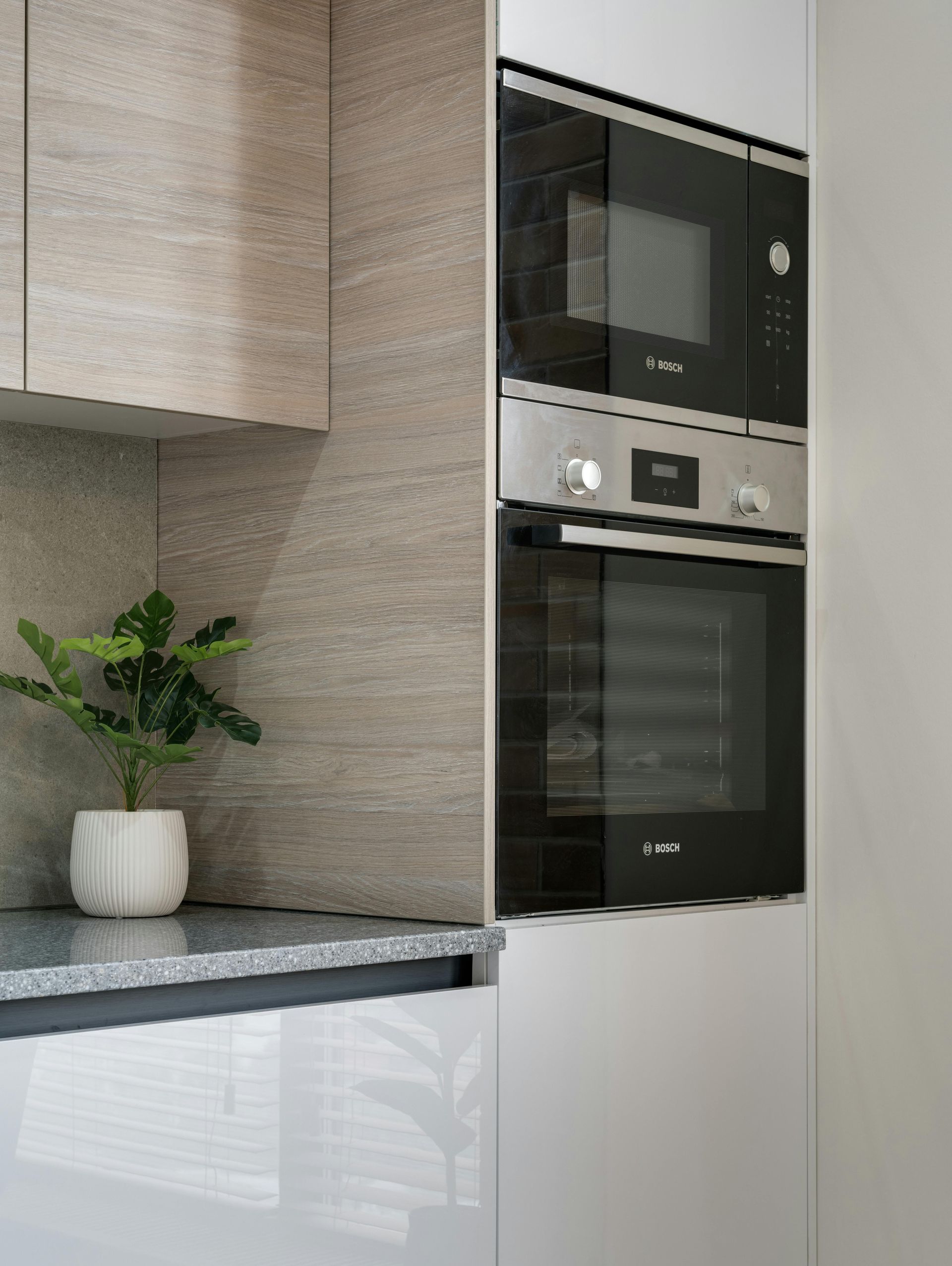 A modern kitchen features white cabinets, granite countertops, a stainless steel microwave and stove, and double windows.