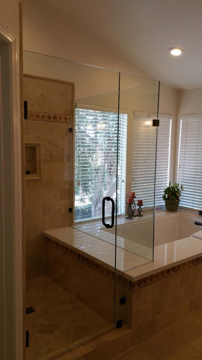 Glass shower enclosure in a bathroom with a bathtub.