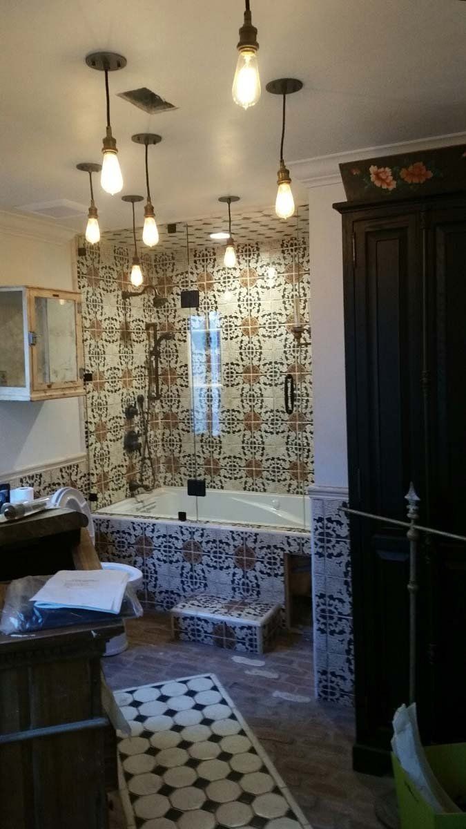 Bathroom with tiled walls, a tub, and multiple hanging light fixtures.