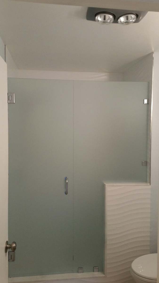 Frosted glass shower stall with a toilet to the right and ceiling fan.