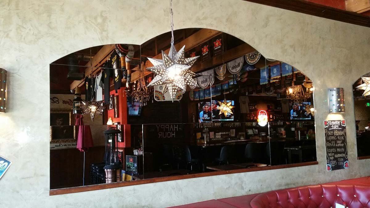 Interior view of a Mexican restaurant with a bar. Red booth seating and a decorated archway.