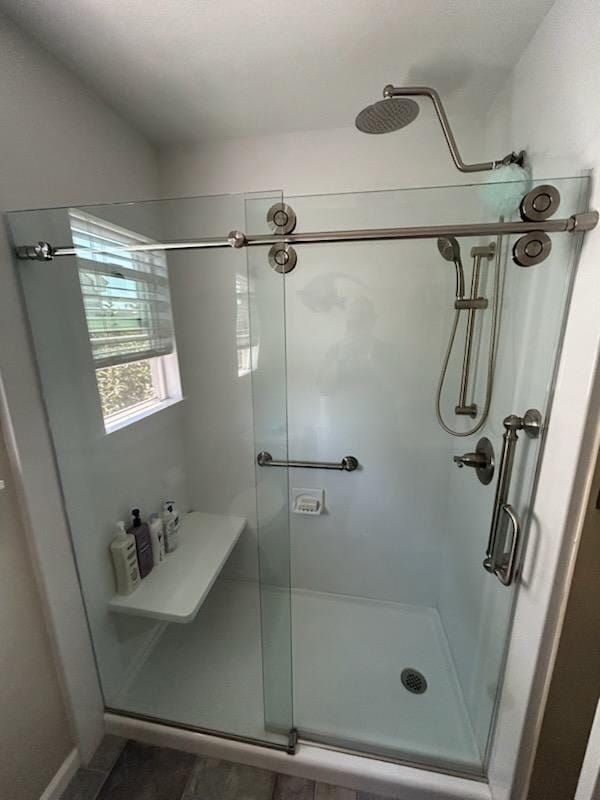 Accessible shower with glass sliding doors, grab bars, showerhead, and a seat.