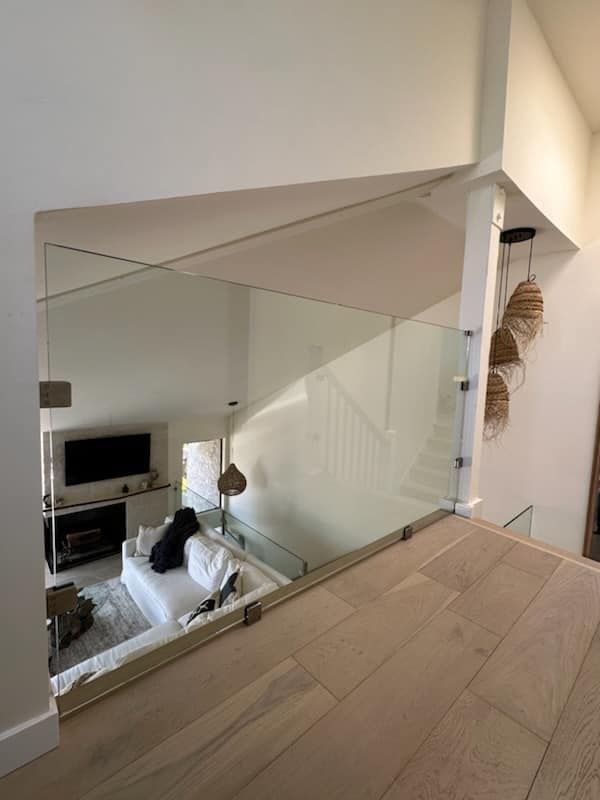 Interior view: modern home with glass railing, white walls, and a staircase.