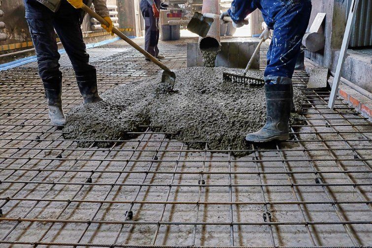Workers Pouring Concrete Over a Metal Grid in a Construction Site — Comet Concreting in Drayton, QLD