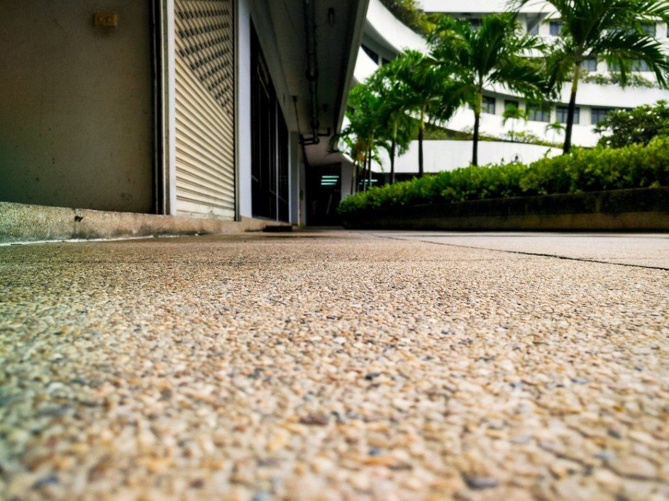 A Pebbled Walkway With a Building on the Left — Comet Concreting in Drayton, QLD