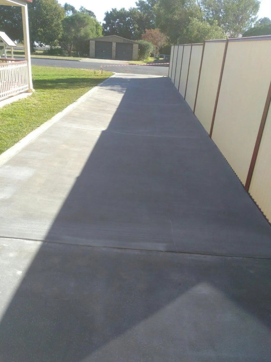 Concrete Driveway With a Fence on the Right and Grass on the Left — Comet Concreting in Drayton, QLD