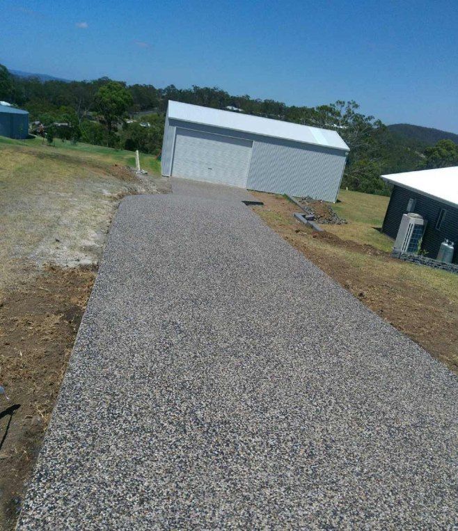 Gravel Driveway Leading to a Metal Shed on a Sunny Day — Comet Concreting in Drayton, QLD