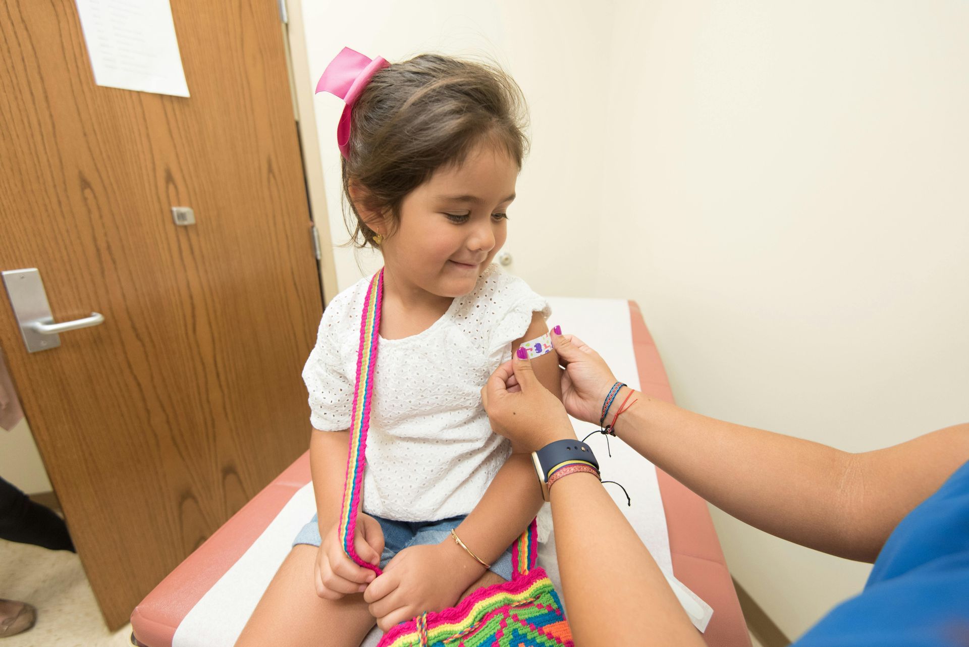 Girl getting a bandage on her arm after a vaccination at a clinic.
