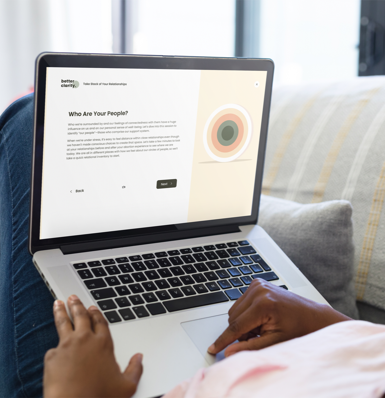 Person using a laptop on a couch, focused on a webpage titled 