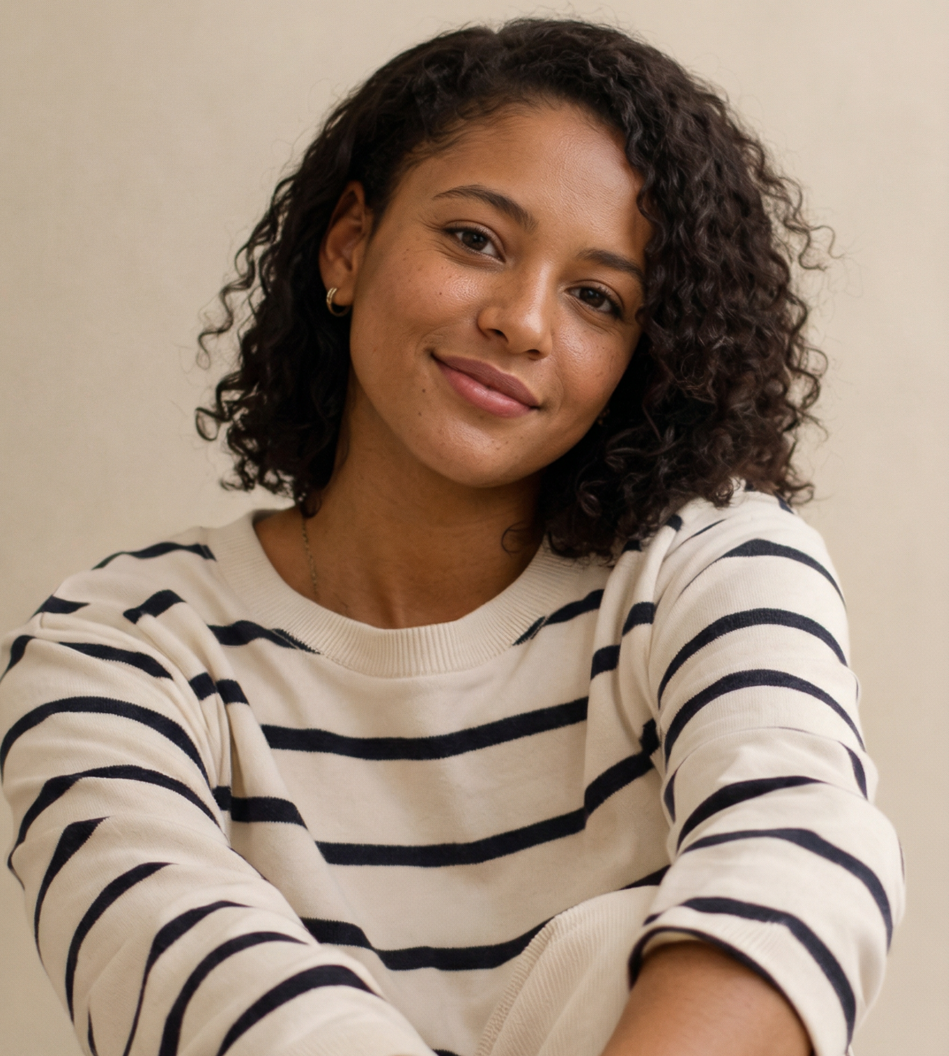 Woman with brown hair and light blue sweater, head resting on her hand, looking towards the camera.