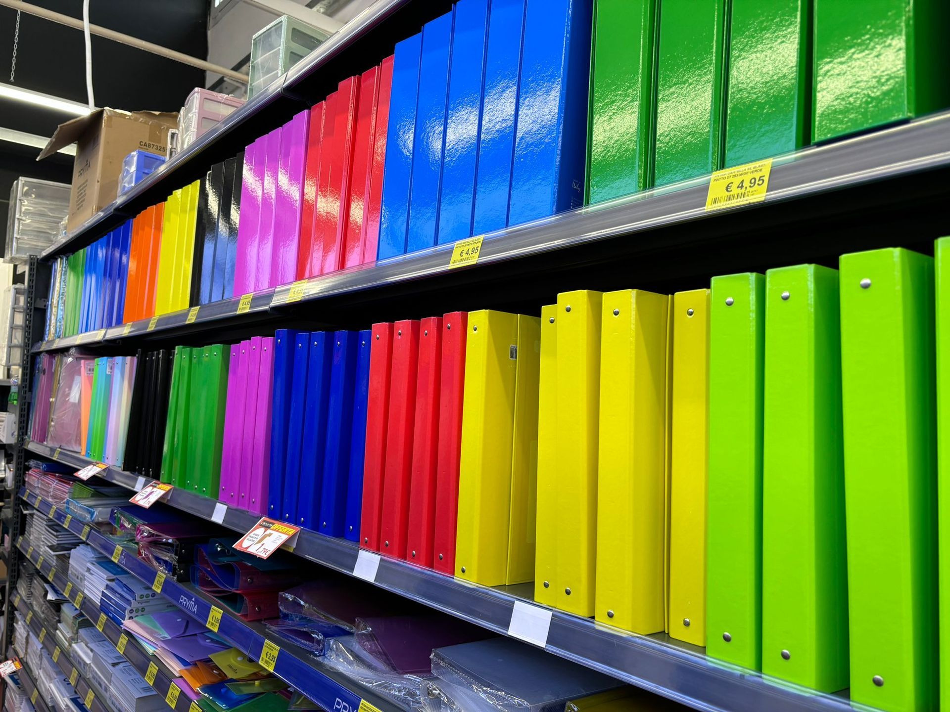 Uno scaffale di un negozio pieno di tanti raccoglitori colorati.