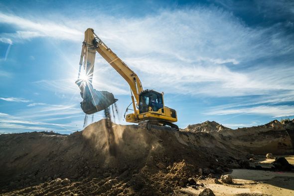 A yellow excavator is digging a hole in the dirt.