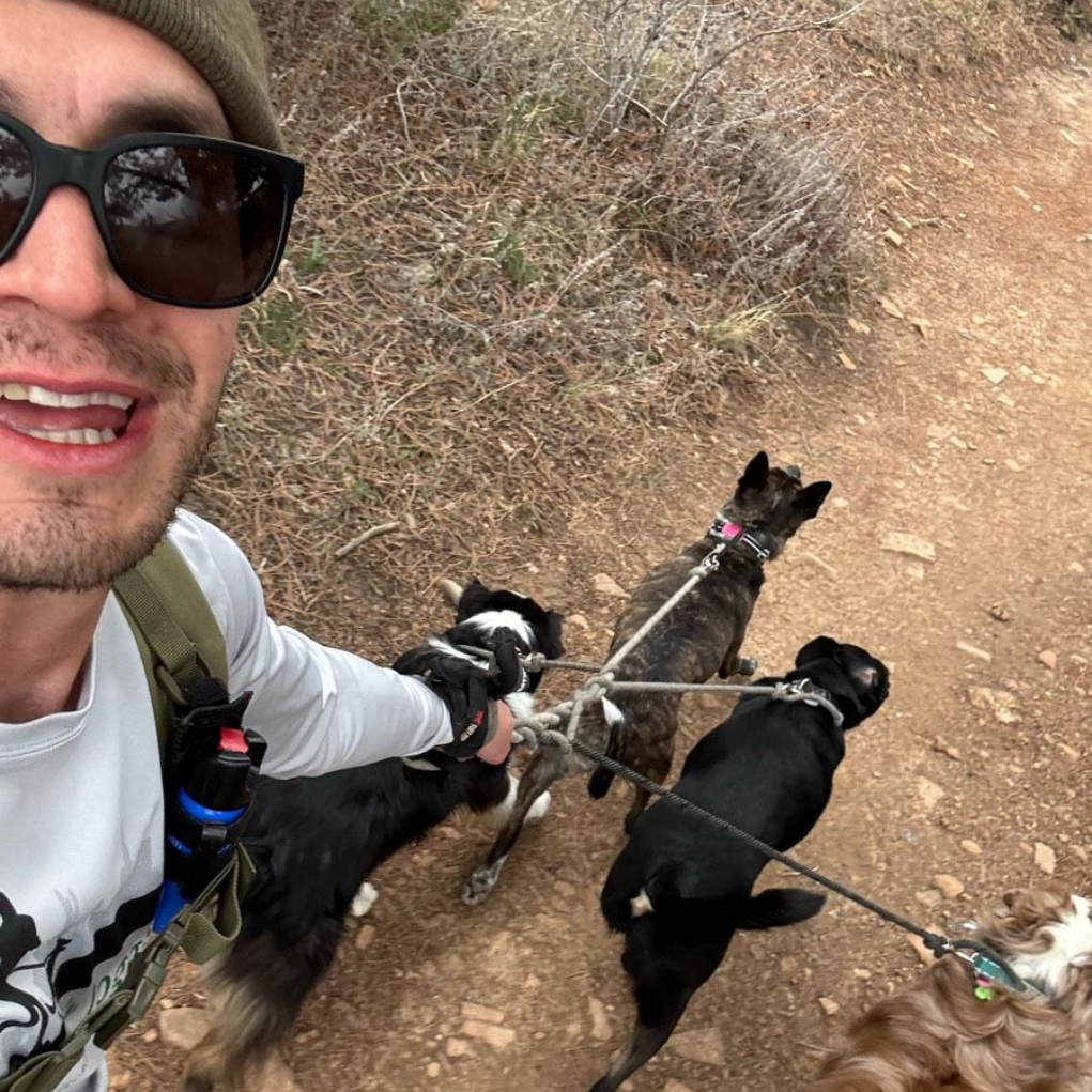 Alex H taking a selfie with a group of dogs.