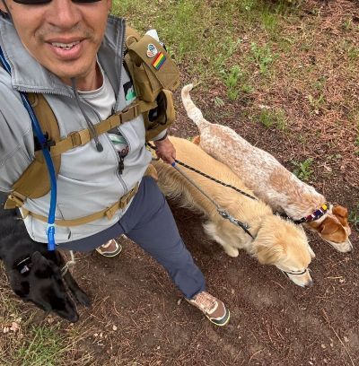 Andrew taking a selfie with three dogs on a hike