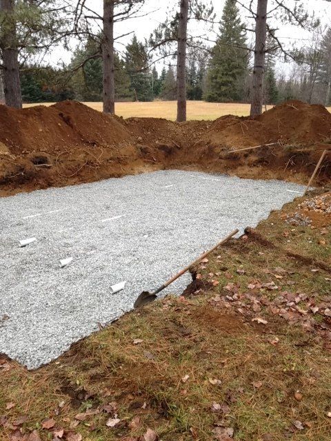 A large pile of dirt and gravel in a field with trees in the background