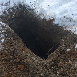 Un trou dans le sol rempli de terre et de neige.
