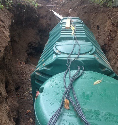 A green septic tank is being installed in a trench