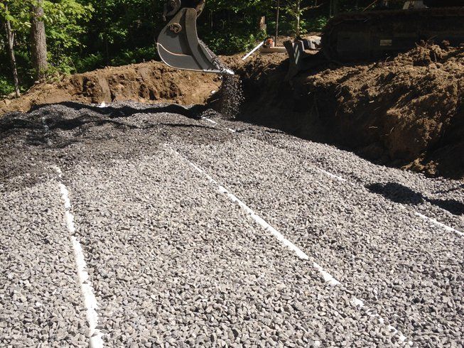 A large pile of gravel with a bulldozer in the background