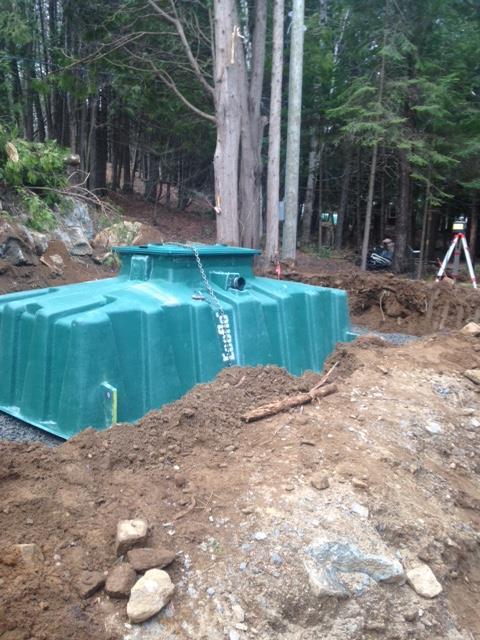 A large green tank is sitting in a pile of dirt in the middle of a forest.