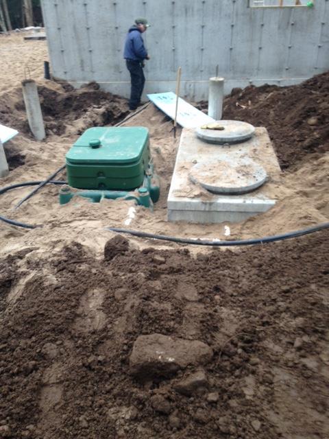 A man is standing in the dirt next to a septic tank.