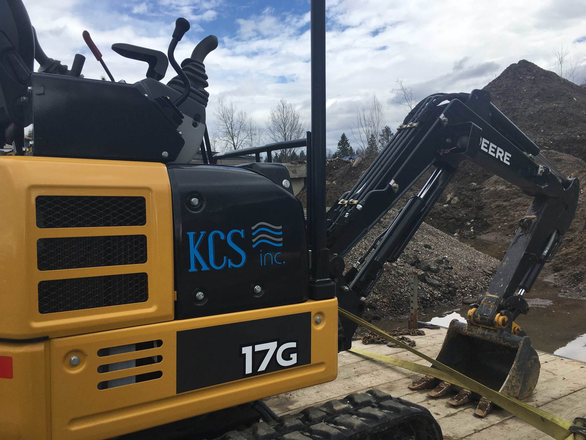 Yellow and black excavator working on a construction site with a pile of rocks.