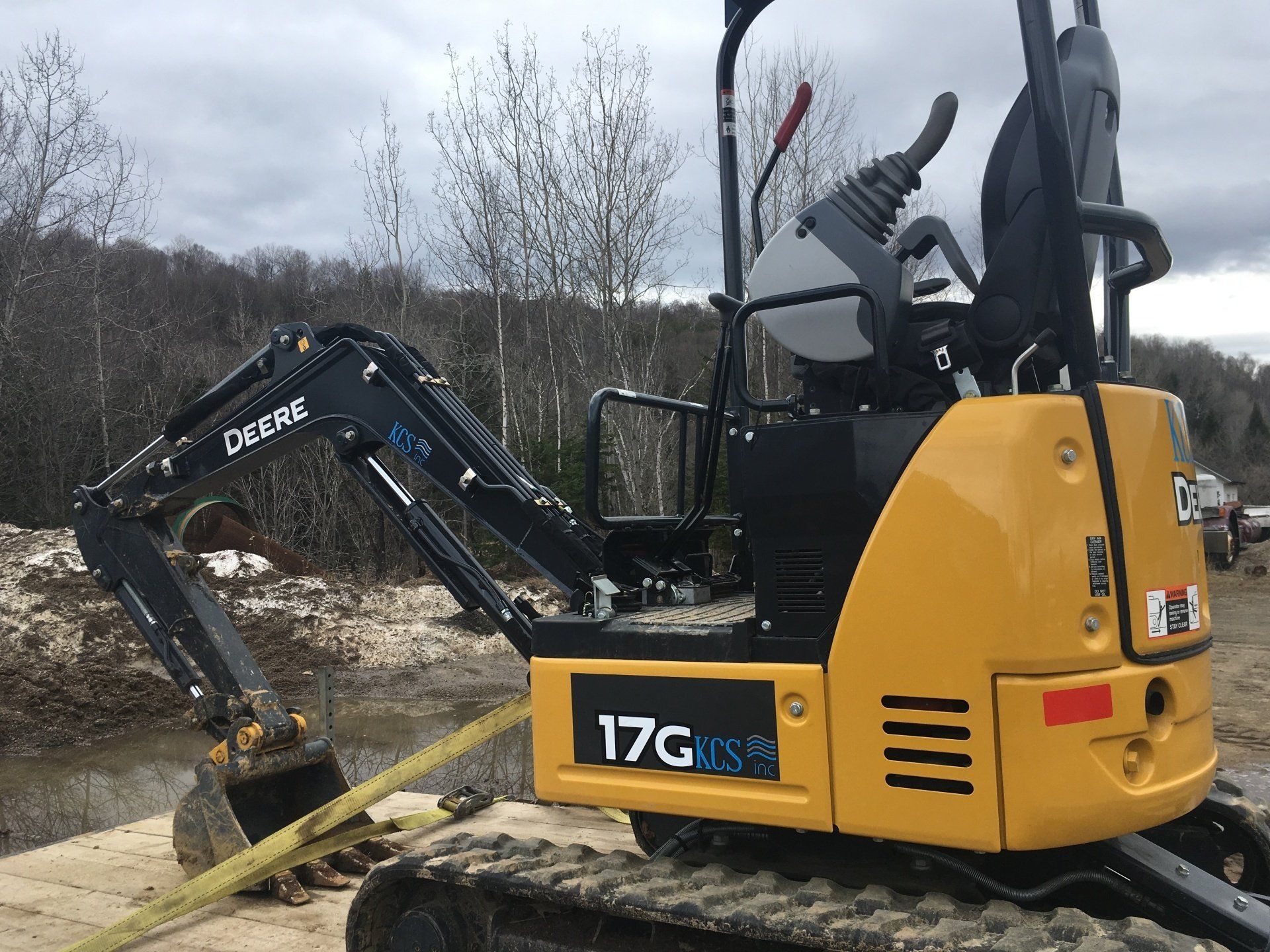 A small yellow excavator is parked on a dirt road.