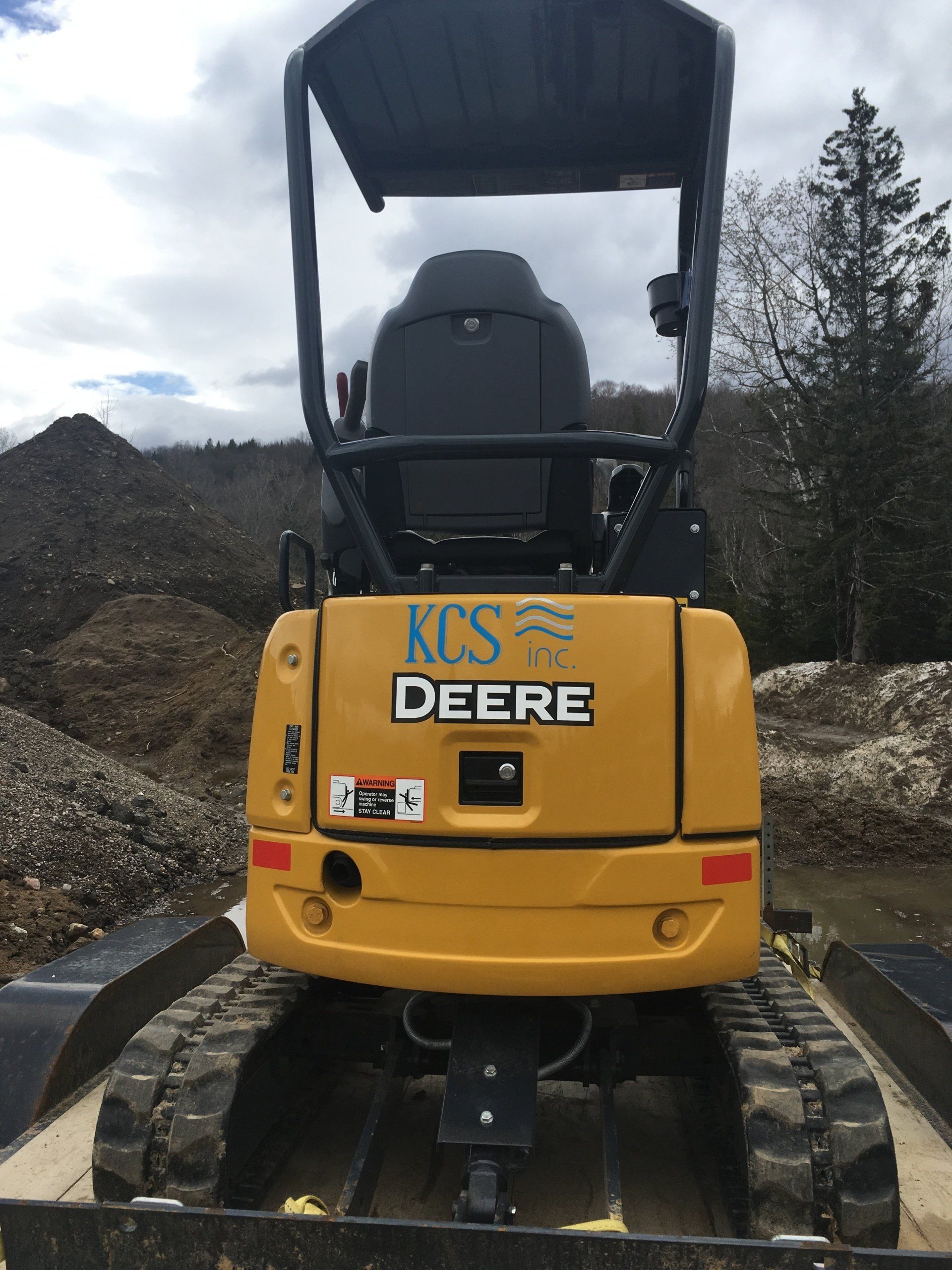 A yellow deere bulldozer is parked in a pile of dirt