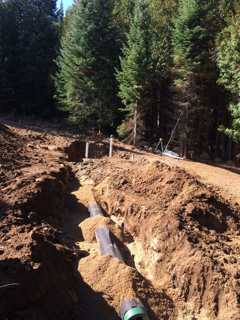 A large pile of dirt with trees in the background