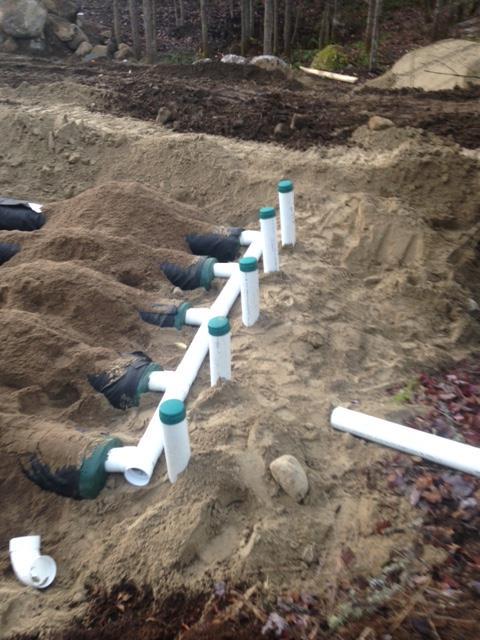 A row of white pipes are laying in the dirt.