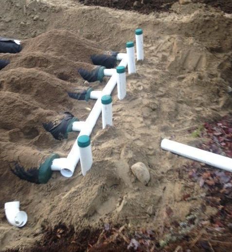 Une rangée de tuyaux blancs posés sur un tas de terre.