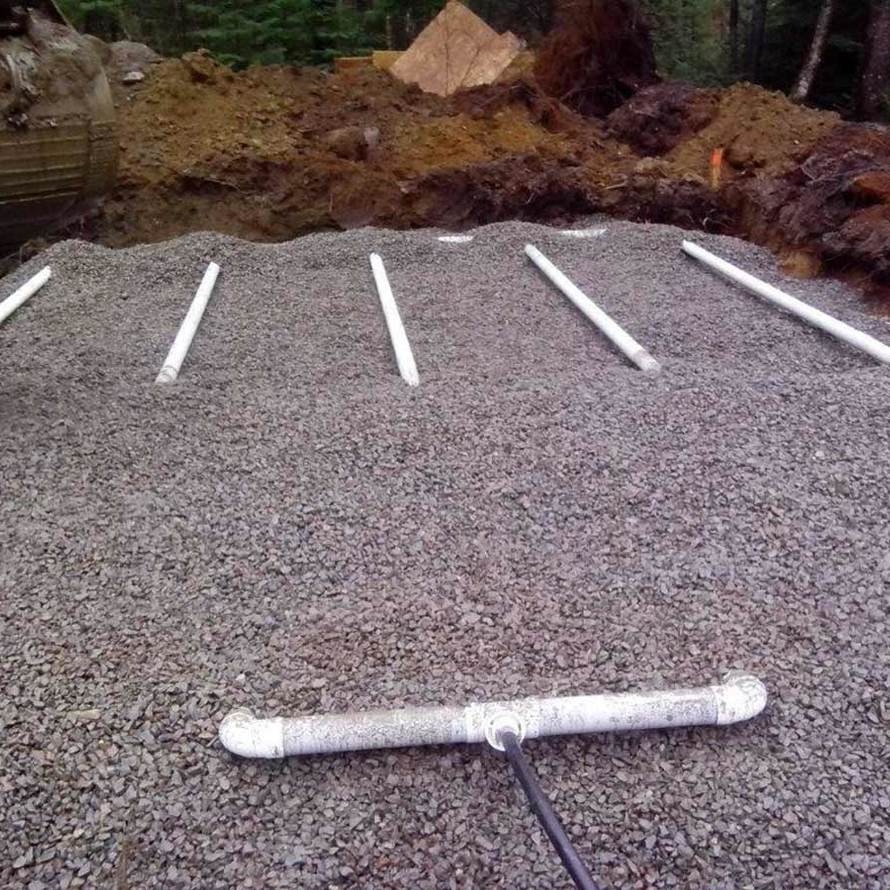 A pile of gravel with pipes sitting on top of it.