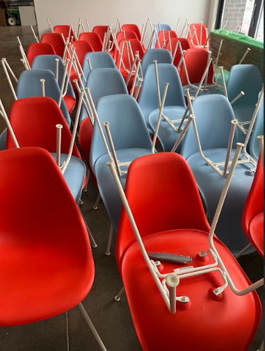 Rows of red and blue chairs stacked upside down on a concrete floor.