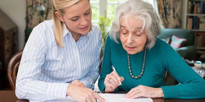 Two women are sitting at a table looking at a piece of paper.