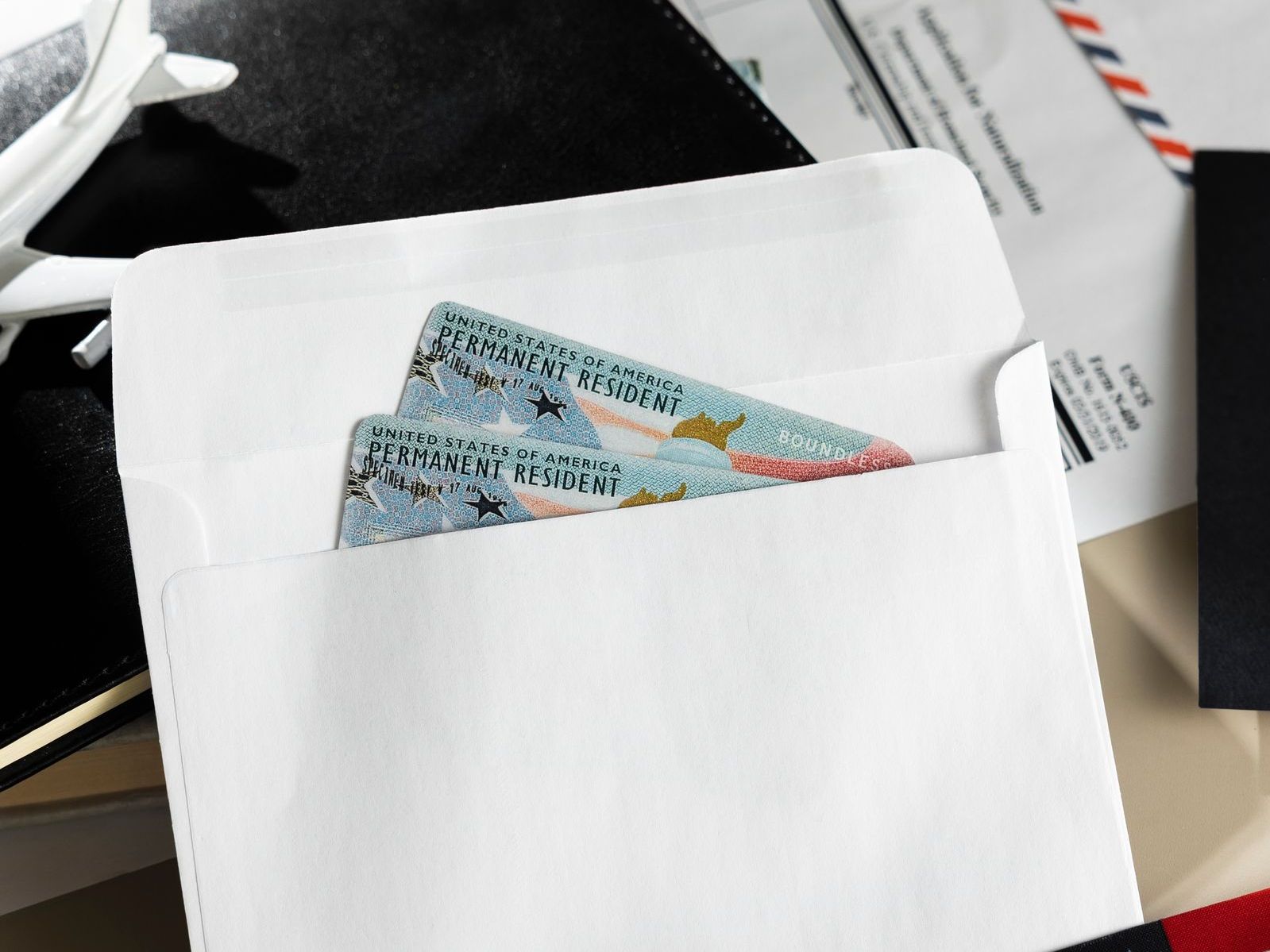 An elderly man in a straw hat is picking flowers from a bush.
