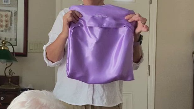 A woman is holding a purple satin top in her hands.
