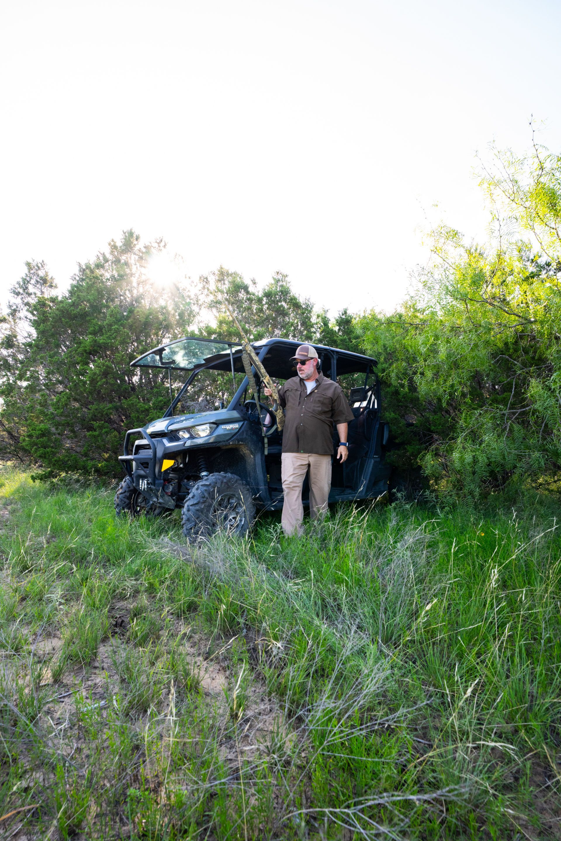 Two people walking outdoors on a rocky path; one wears a green shirt and shorts, the other a black shirt and shorts.